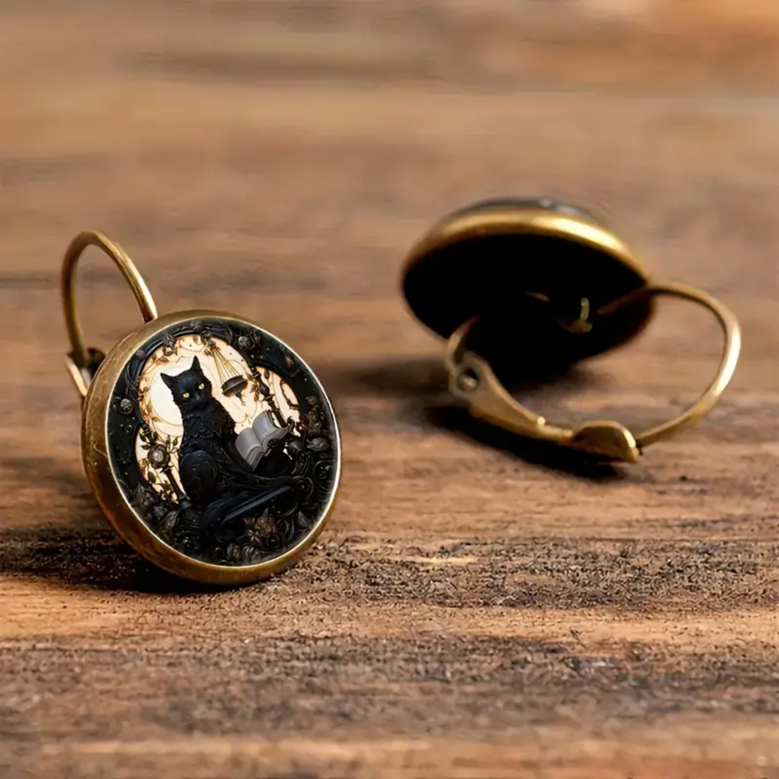 Pair of earrings with black cat design on a wooden surface