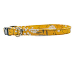 A yellow cat collar with a white floral pattern and a black plastic buckle, displayed on a clean white background.