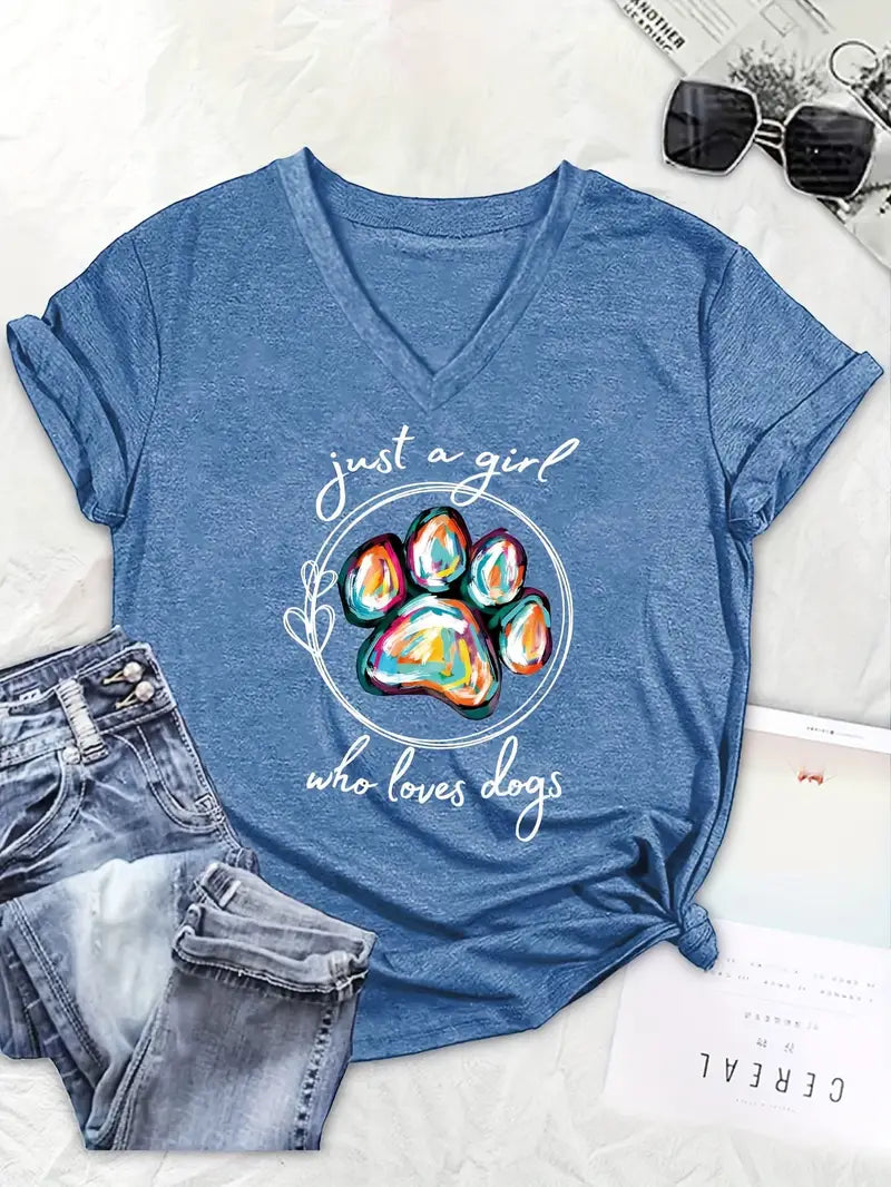 Blue t-shirt with colorful paw print and text 'just a girl who loves dogs' on a white surface with jeans and sunglasses.