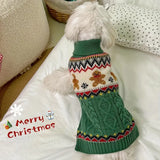 Dog wearing a green Christmas-themed sweater on a white couch.