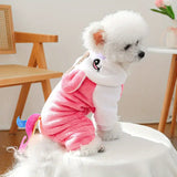 Small white dog wearing a pink and white outfit with bunny ears on a white surface.