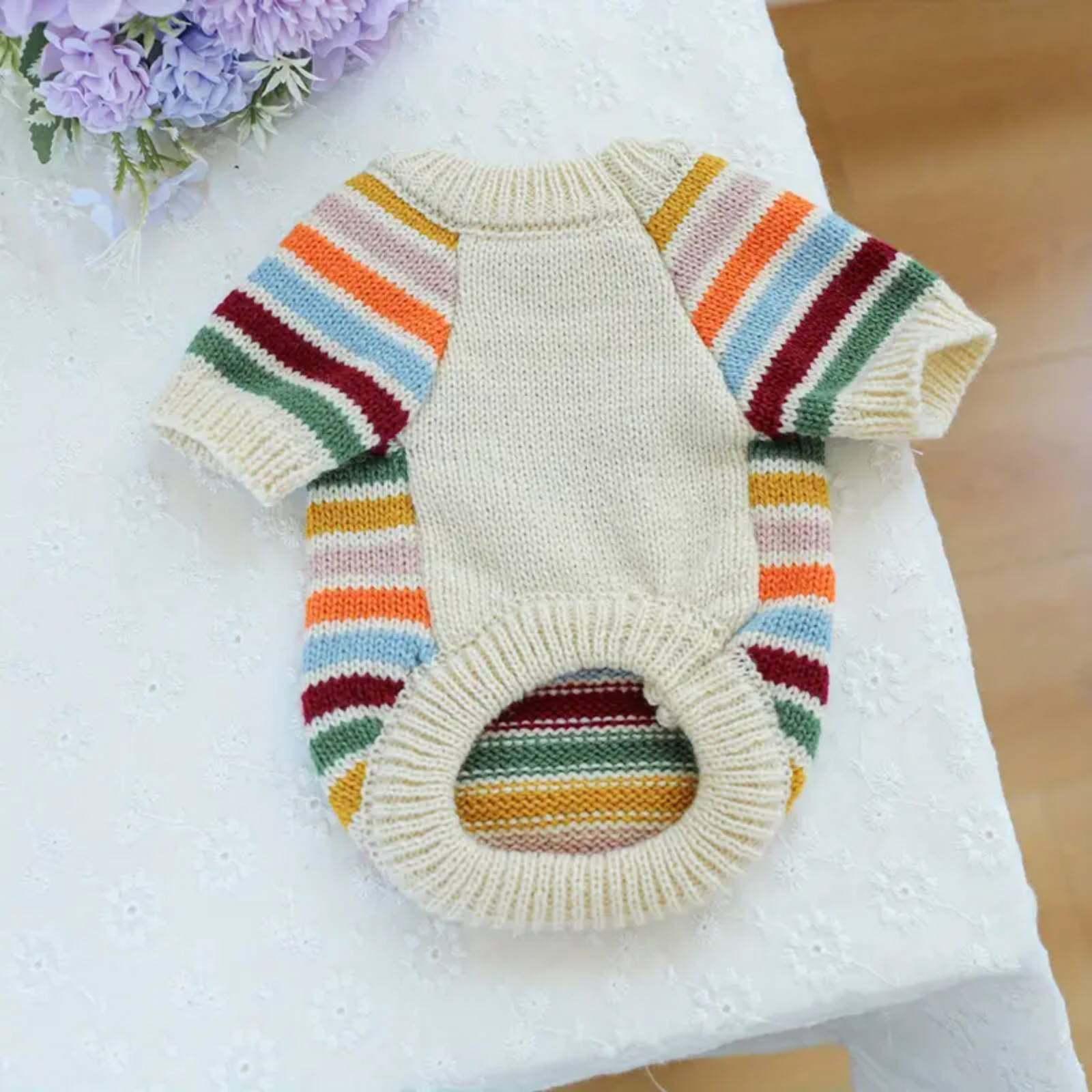 Knitted dog sweater with colorful stripes on a white surface