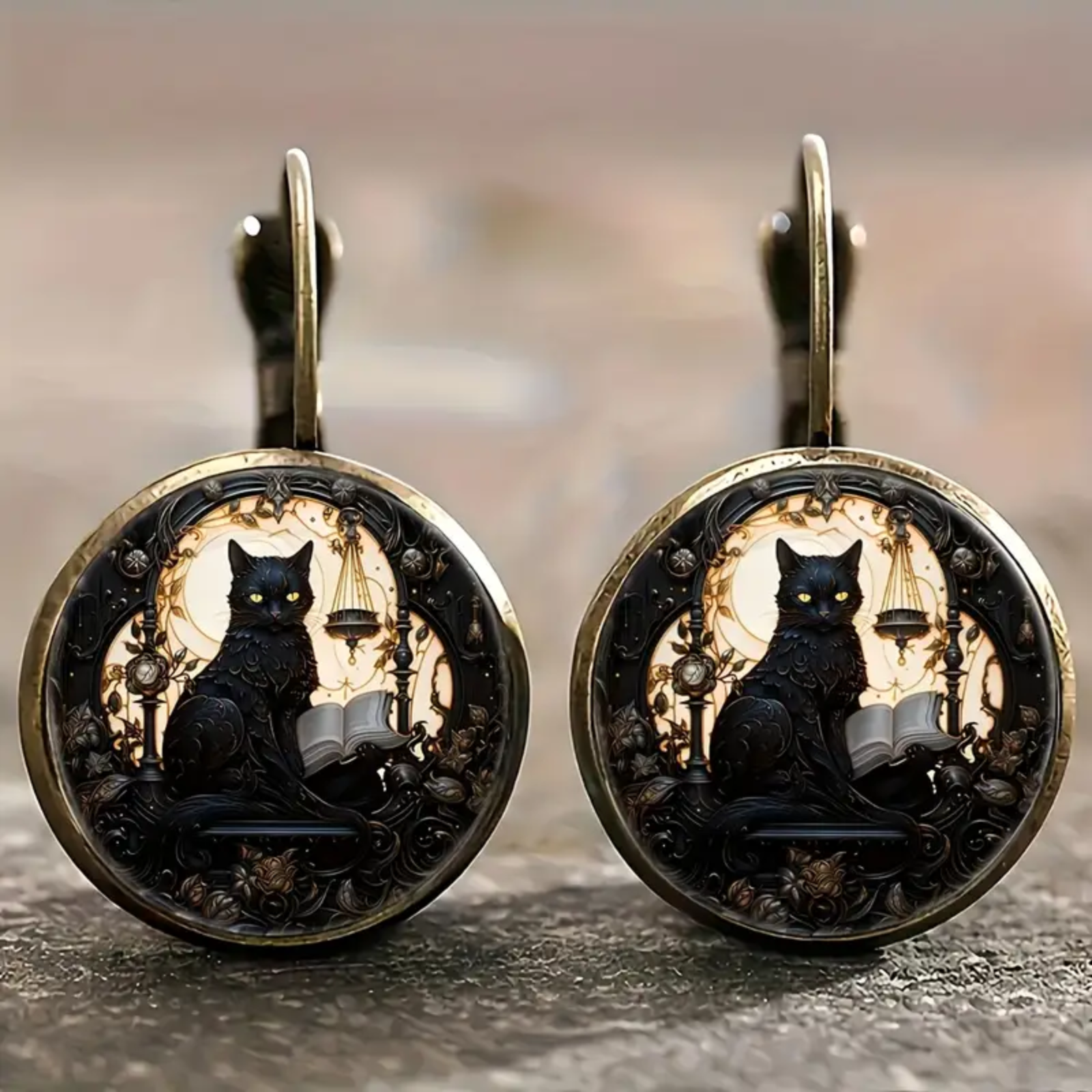 Pair of earrings with black cat design on a blurred background