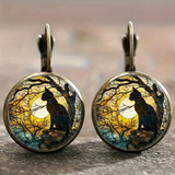 Pair of earrings with cat silhouette design against a moonlit sky.