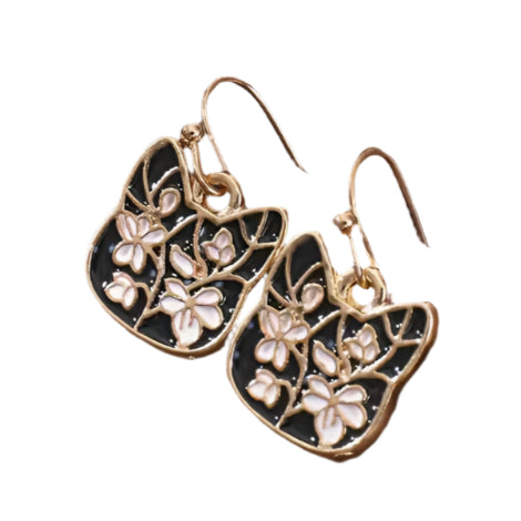 Pair of gold and black floral earrings on a wooden surface