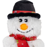 A plush snowman toy with white faux fur, a black top hat with a red band, and a red scarf with green and white holiday motifs, shown against a plain white background.