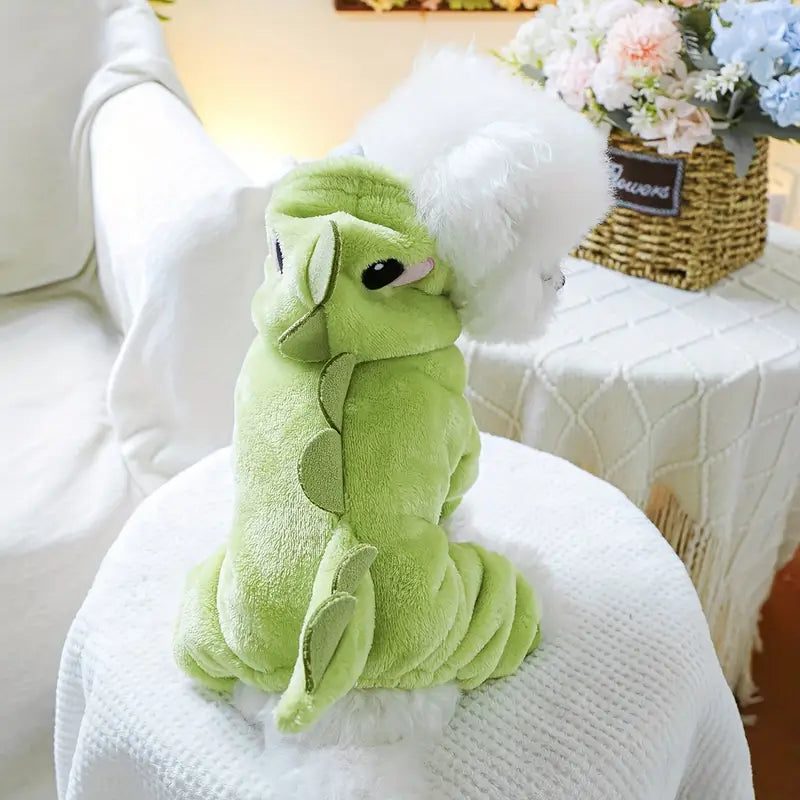 Green plush toy on a white surface with a blurred background