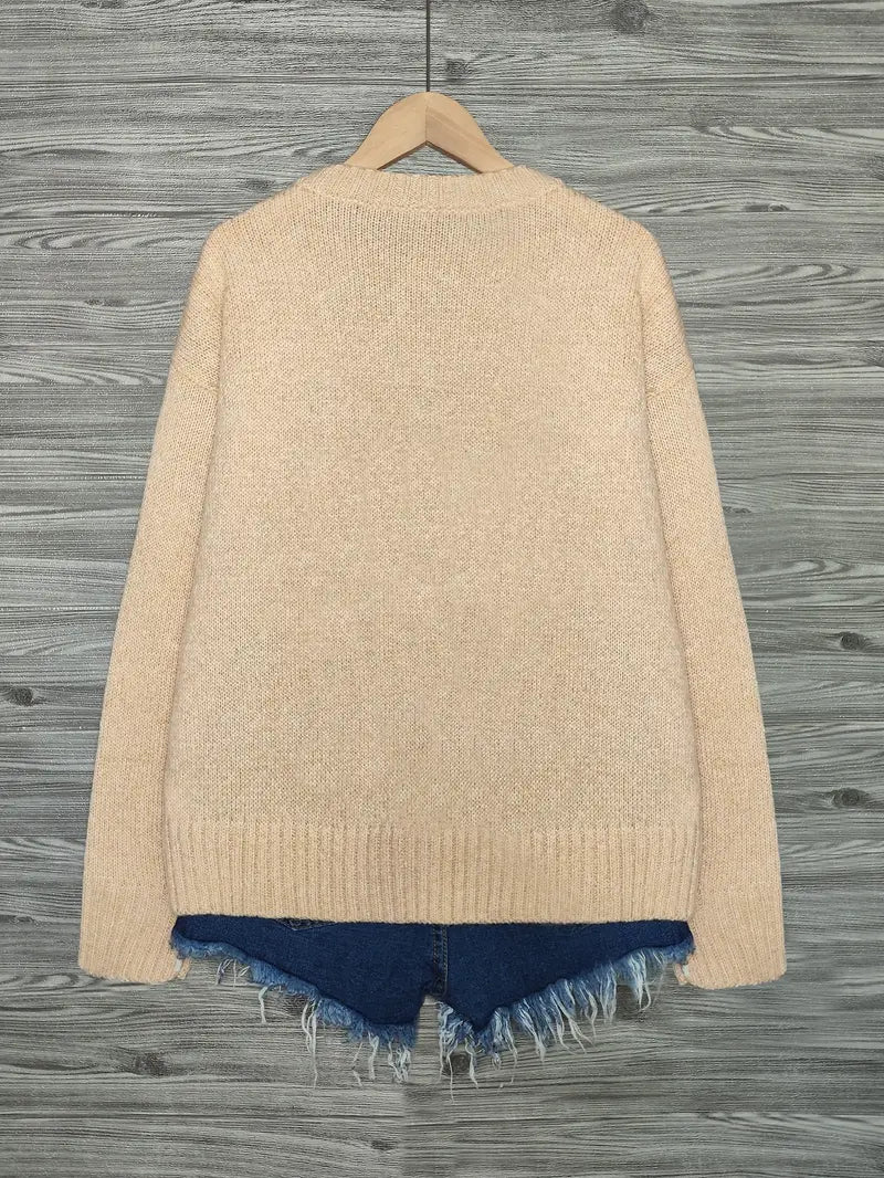 Beige cardigan with blue hem on a wooden surface