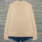 Beige cardigan with blue hem on a wooden surface