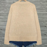 Beige cardigan with blue hem on a wooden surface