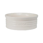 A glossy ivory ceramic pet bowl with raised artistic details and the word 'WOOF' embossed on the side.