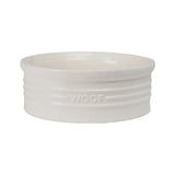 A glossy ivory ceramic pet bowl with raised artistic details and the word 'WOOF' embossed on the side.