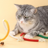 Gray cat playing with colorful cat toys on a beige background