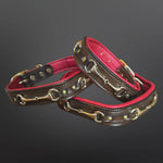 Two brown leather collars with brass hardware and a vibrant pink lining, arranged on a dark gray gradient background.