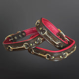 Two brown leather collars with brass hardware and a vibrant pink lining, arranged on a dark gray gradient background.