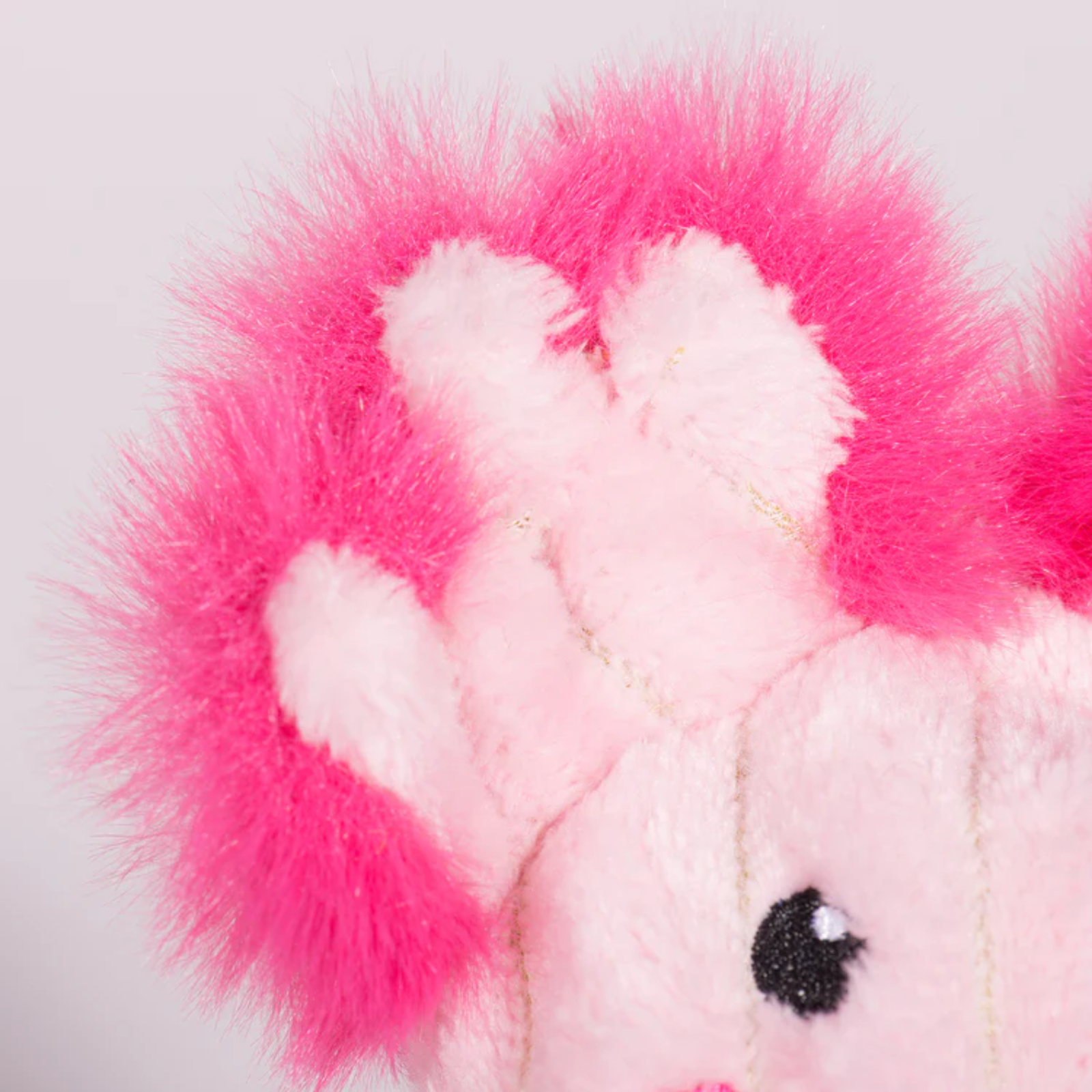 Close-up of a pink plush toy with a fluffy pink heart on a white background