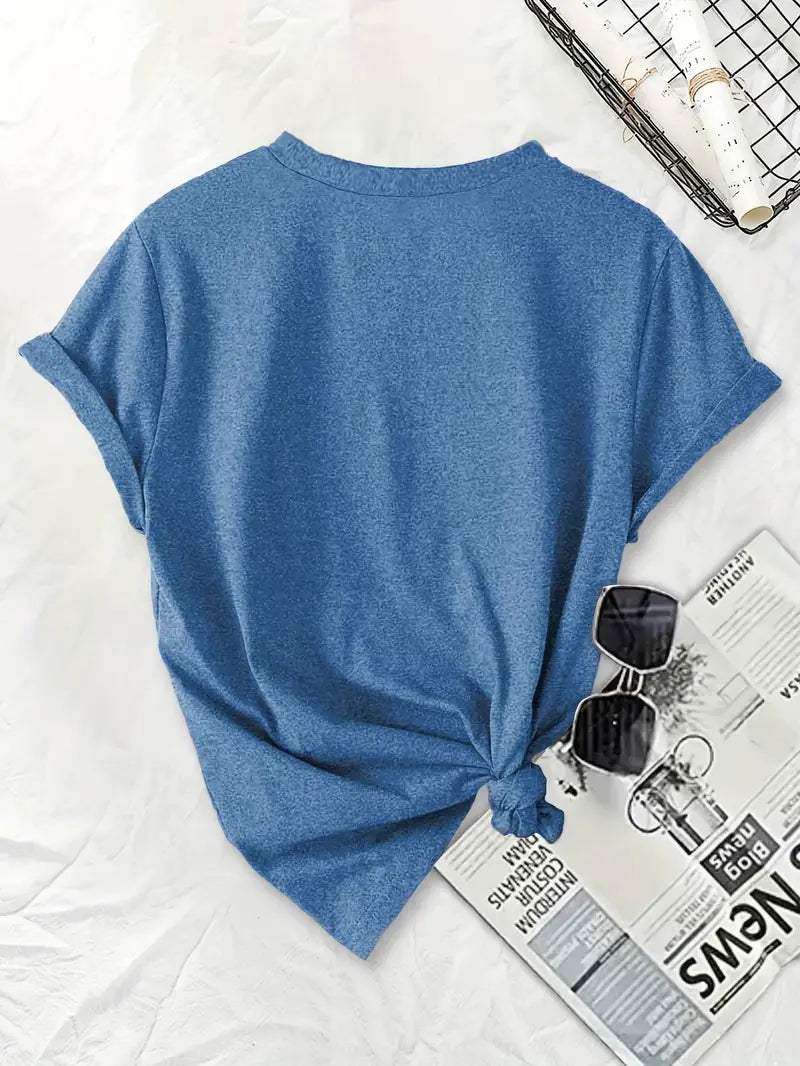 Blue t-shirt with a knot on a white surface with sunglasses and a newspaper.