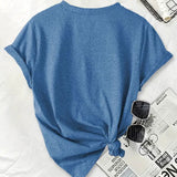 Blue t-shirt with a knot on a white surface with sunglasses and a newspaper.