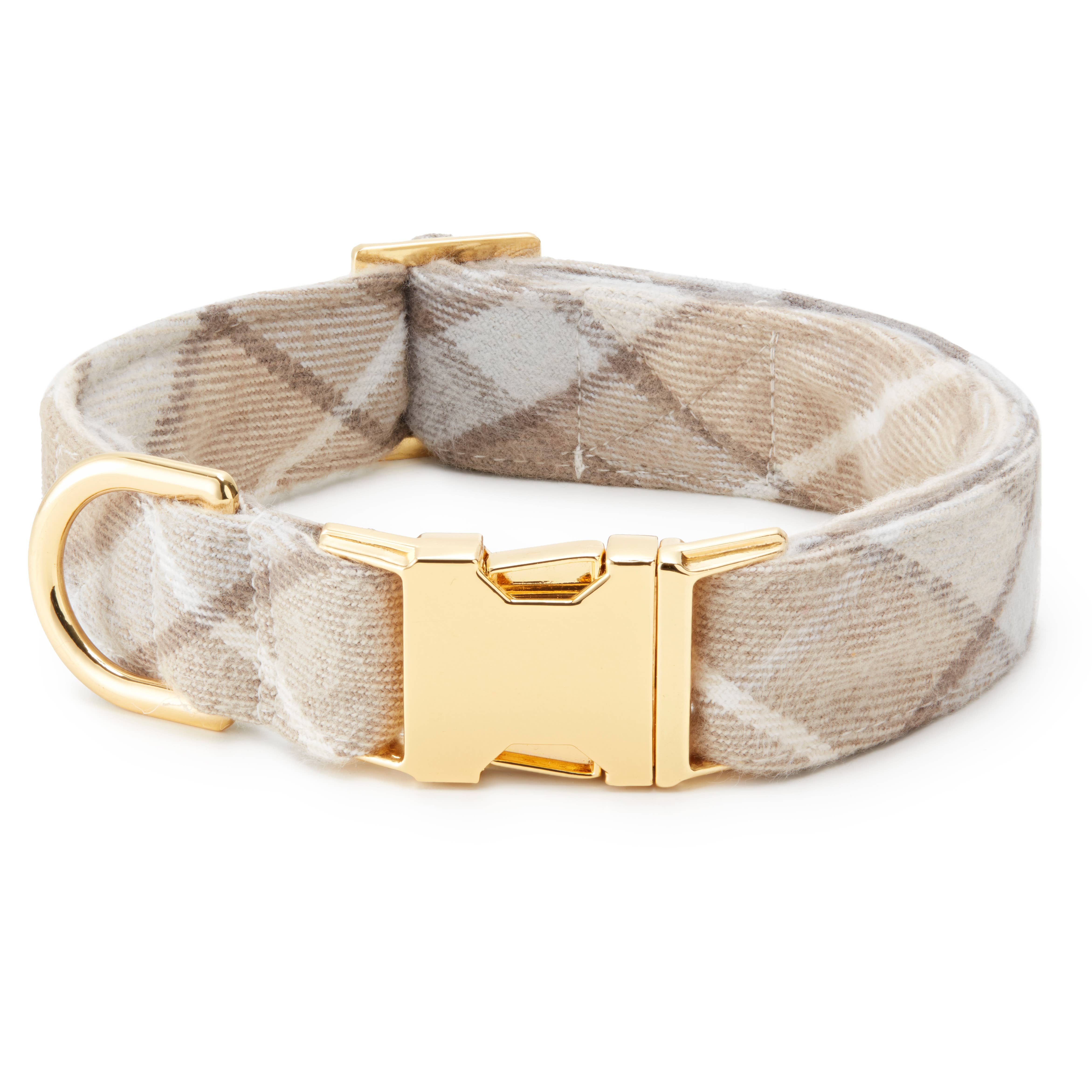 A dog collar with a beige and white argyle patterned fabric strap and a polished gold-tone metal buckle and D-ring, shown on a plain white background.