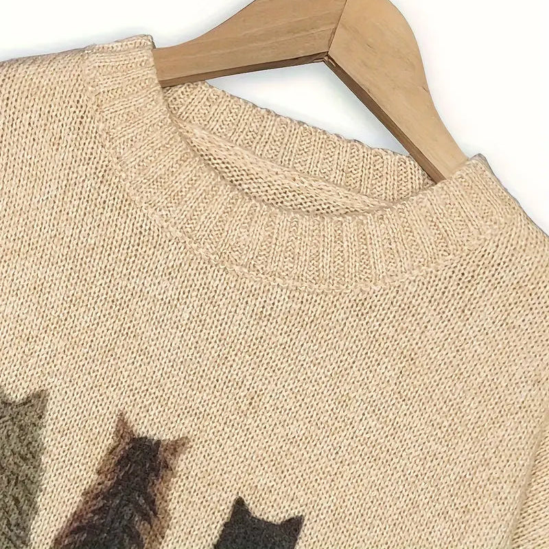 Beige sweater with cat pattern on a wooden hanger against a white background