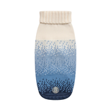 A knit pet sweater with a cream ribbed collar and a blue gradient pattern fading from cream to light blue to dark navy, featuring a circular logo patch near the bottom.
