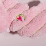 Close-up of pink plush toy with embroidered design on a light background