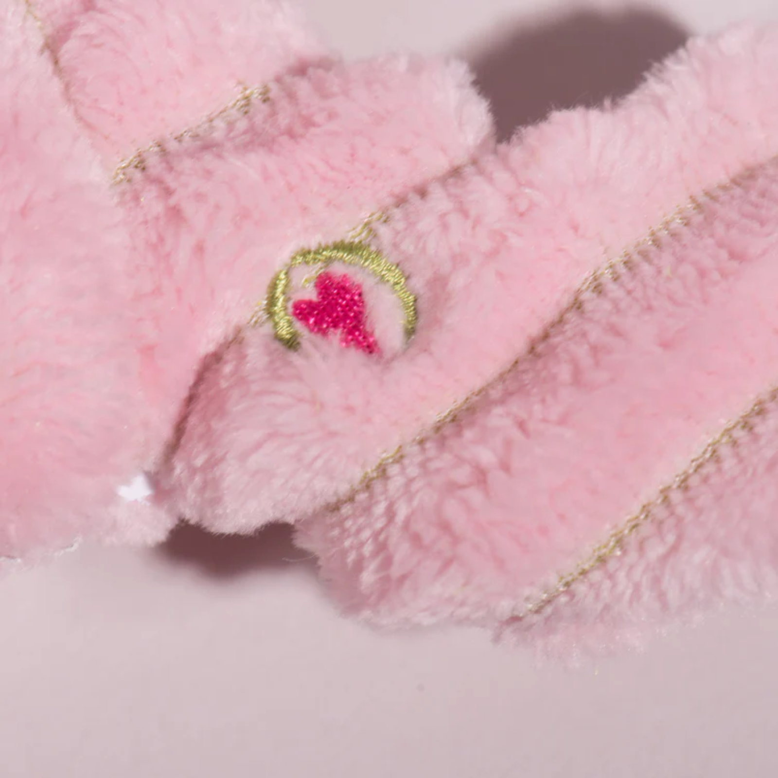 Close-up of pink plush toy with embroidered design on a light background