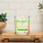 Pet House Candle on a wooden stand with a white tiled wall and decorative items in the background