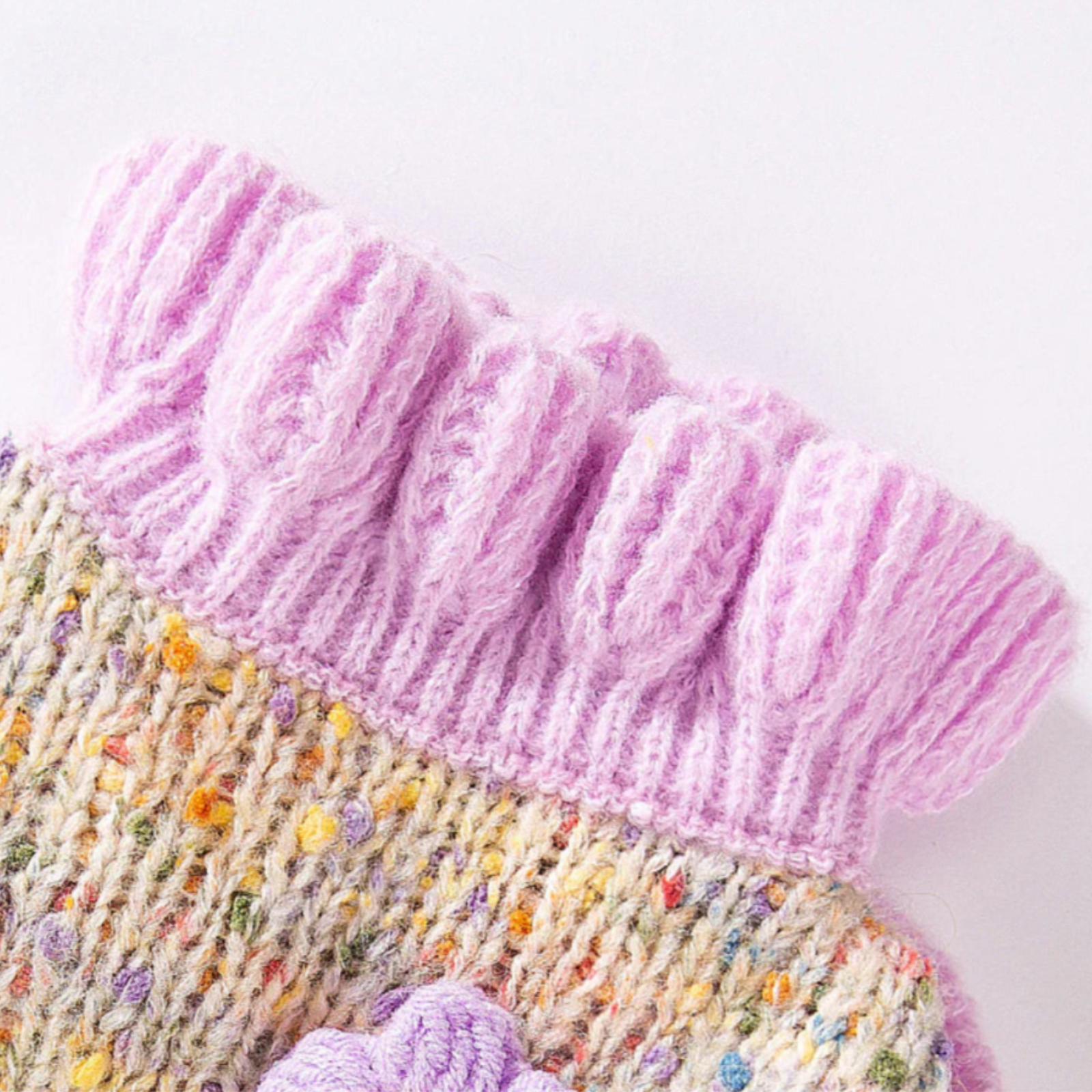 Close-up of a knitted item with pink and multicolored yarn on a white background