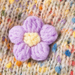 Knitted purple flower on a textured fabric background