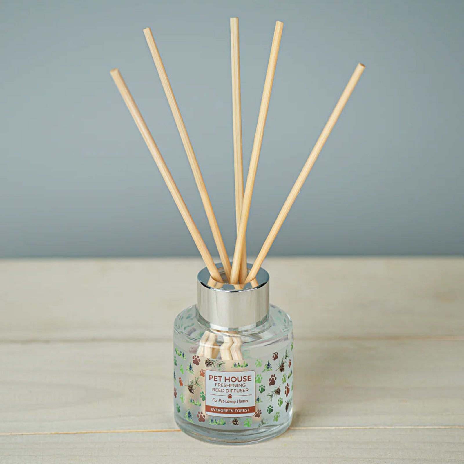 Reed diffuser with wooden sticks in a glass bottle on a wooden surface.