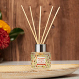 Diffuser with wooden sticks on a decorative plate with flowers in the background