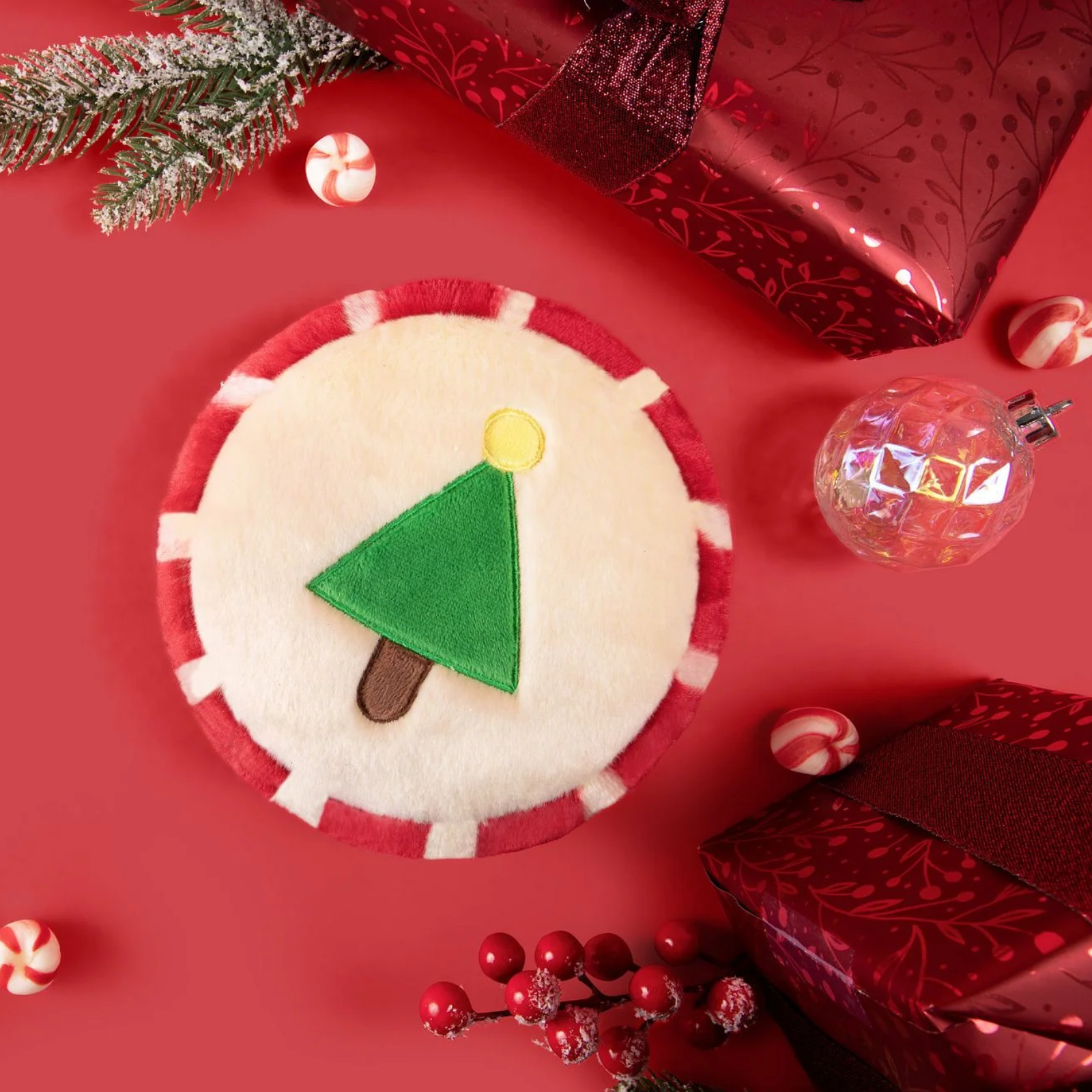 Decorative item with a Christmas tree design on a red background with festive elements.