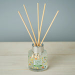Reed diffuser with wooden sticks in a glass bottle on a wooden surface with a gray background