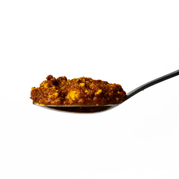 Spoonful of brown spice mix on a white background