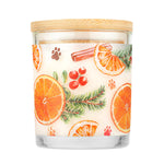 Candle with a decorative label featuring oranges, cinnamon sticks, and berries on a white background