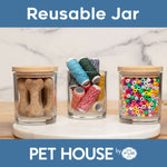 Three glass jars with wooden lids containing dog treats, spools of thread, and colorful beads on a marble surface. Brand 'PET HOUSE by FUR' visible.