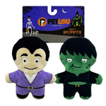 Two plush Halloween dog toys on a white background with their retail card. The left toy is a vampire character with a purple suit, and the right toy is a green monster character in a black suit.