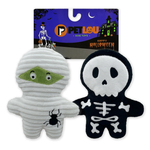 Two Halloween-themed plush dog toys displayed in front of their retail packaging. The left toy is a white mummy figure with a green eye patch and a black spider on its belly.