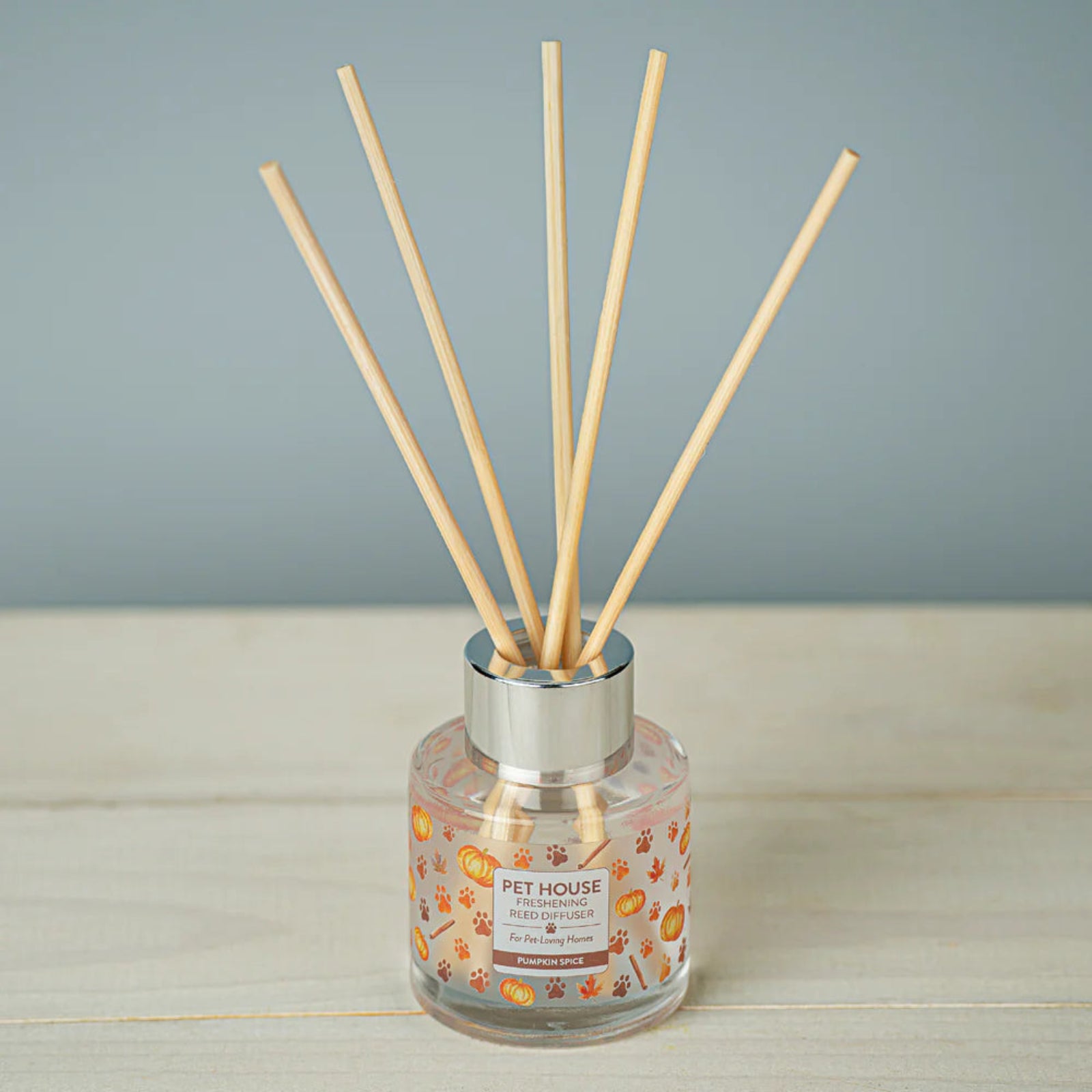 Reed diffuser with wooden sticks in a clear bottle on a wooden surface with a gray background