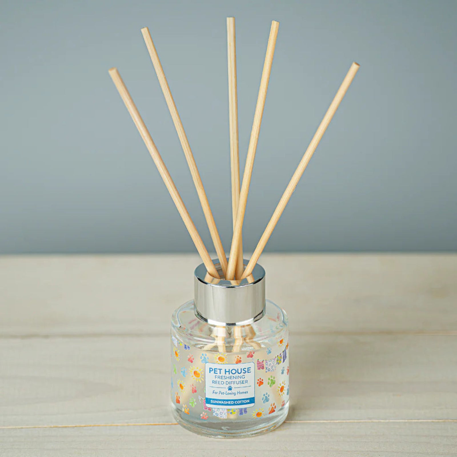 Reed diffuser with wooden sticks in a glass bottle on a wooden surface with a gray background