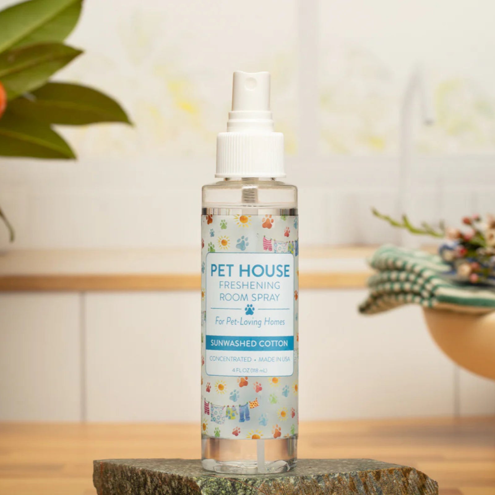 Bottle of Pet House room spray on a wooden surface with a blurred background