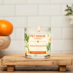 Pet House Candle on a wooden stand with mandarin orange and sage design, surrounded by fruits and flowers.