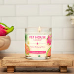 Pet House Candle with tropical fruit design on a wooden stand, with a pink fruit and flowers in the background.
