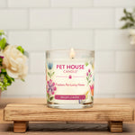 Pet House Candle with floral design on a wooden stand with flowers in the background