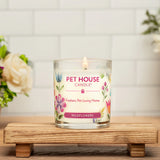 Pet House Candle with floral design on a wooden stand with flowers in the background