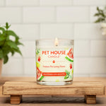 Pet House Candle on a wooden stand with plants and flowers in the background