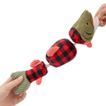 A plush fishing rod toy being held by two hands against a white background. The toy features olive green plush fish heads and tails with red and black buffalo plaid sections in the middle, pinkish-red fins, and a rope handle.
