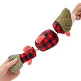 A plush fishing rod toy being held by two hands against a white background. The toy features olive green plush fish heads and tails with red and black buffalo plaid sections in the middle, pinkish-red fins, and a rope handle.