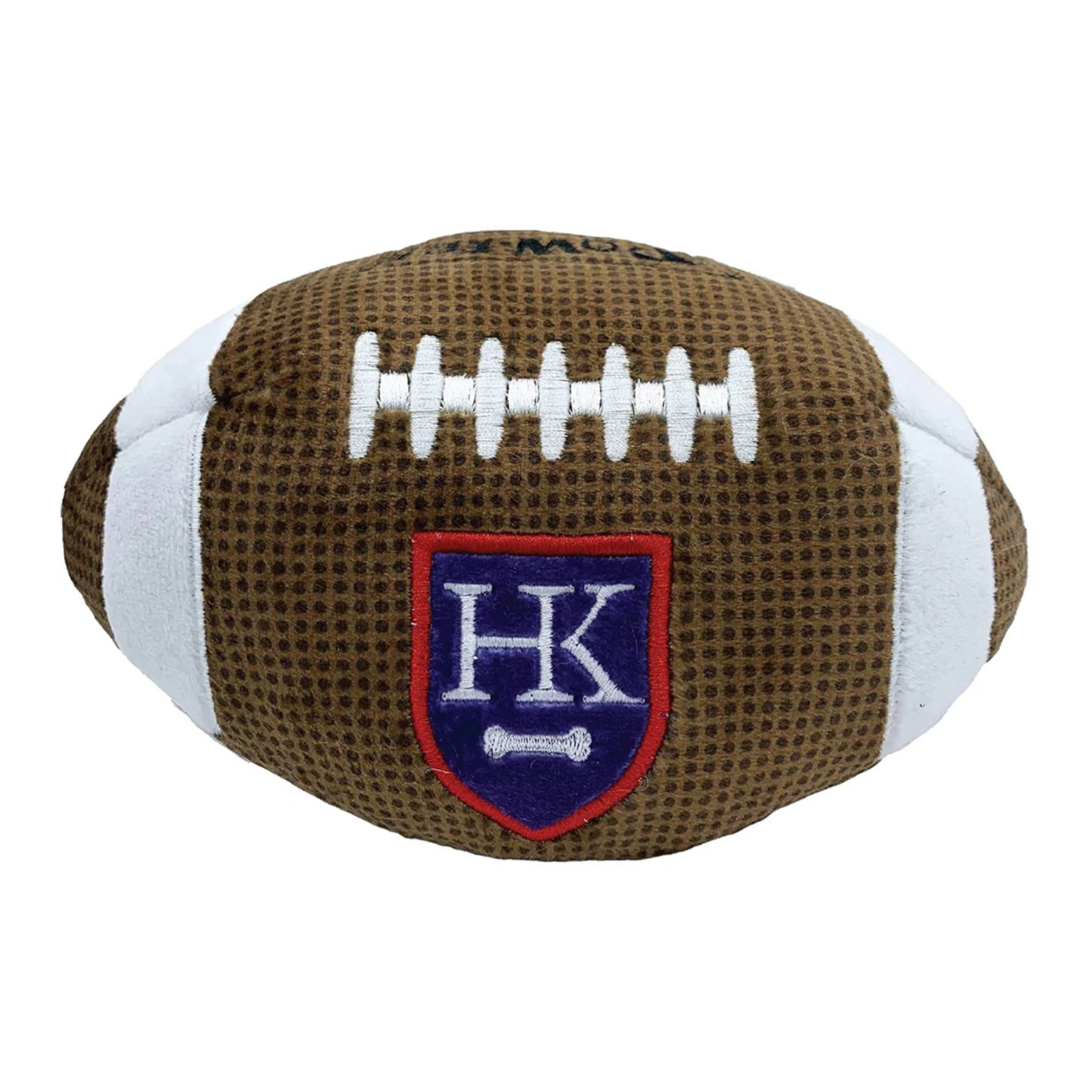 A plush football-shaped pet toy in brown and white, featuring a blue and red shield patch with the letters 'HK' and a small white bone.